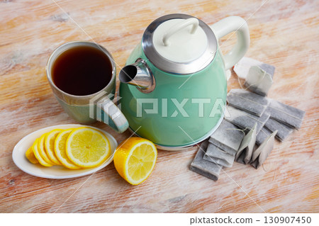 New teapot on table with cup of black tea and sliced lemon 130907450