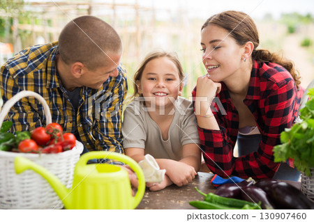 Couple of gardeners with child posing with harvest of vegetables 130907460
