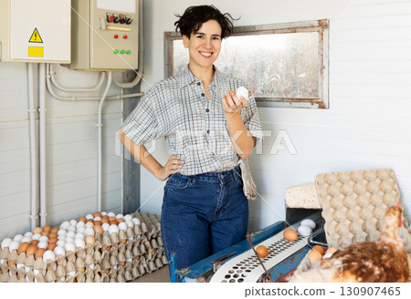 Happy Latin female farmer sorting and packing chicken eggs on farm 130907465