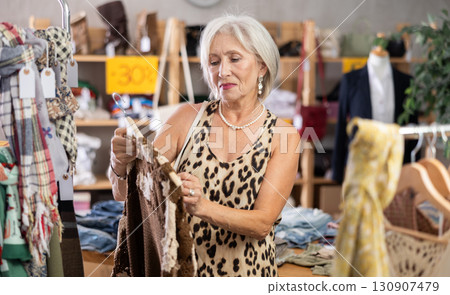 Elderly woman chooses cardigan in clothing store 130907479