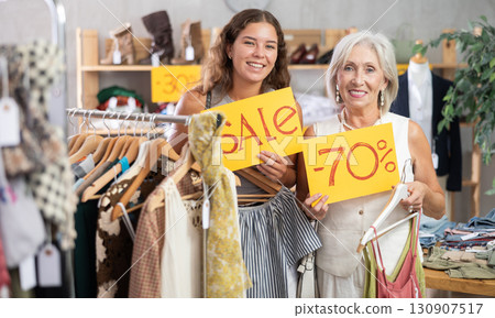 Two positive women holding sale banner in clothing store 130907517