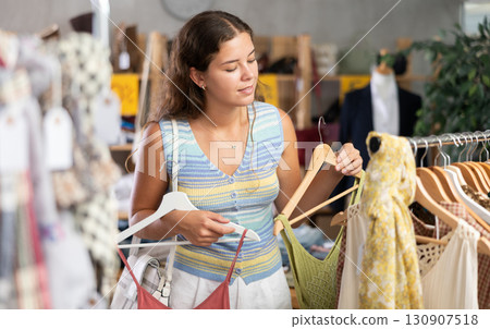 Young woman choosing summer clothes in store 130907518