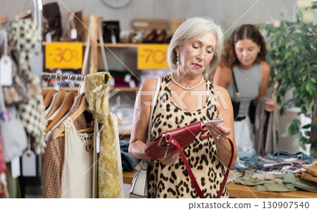 Elderly woman choosing a fashionable handbag in boutique 130907540