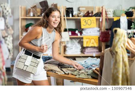 Search and selection of new jeans in a clothing store for young woman Search and selection of new jeans in a clothing store for young woman 130907546