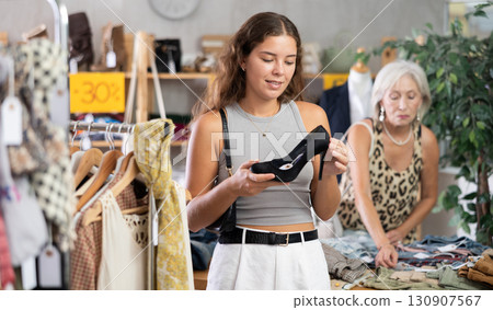 Young woman choosing high heel shoes in store Young woman choosing high heel shoes in store 130907567