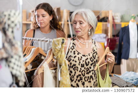 Elderly and young women choosing summer clothes in store 130907572