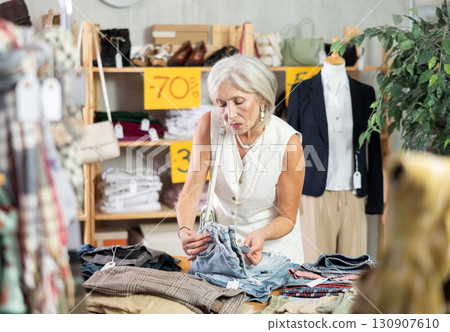 Elderly woman choosing jeans in clothing store Elderly woman choosing jeans in clothing store 130907610