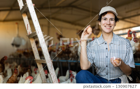 Young Latin female farmer picking fresh chicken eggs in coop Young Latin female farmer picking fresh chicken eggs in coop 130907627