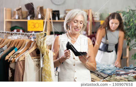 Mature woman chooses fashionable shoes in prestigious store 130907658