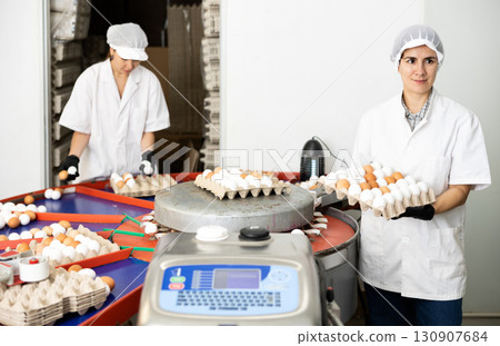 group of people in lab coats and hairnets doing egg quality control in chicken farm 130907684