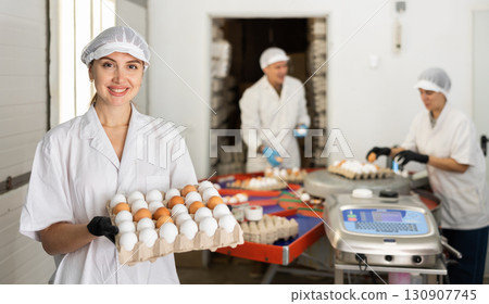 group of people in lab coats and hairnets doing egg quality control in chicken farm group of people in lab coats and hairnets doing egg quality control in chicken farm 130907745