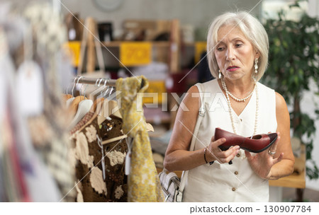 Mature woman chooses fashionable shoes in prestigious store Mature woman chooses fashionable shoes in prestigious store 130907784