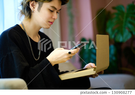 A man from Generation Z operating a smartphone in front of his luggage 130908277