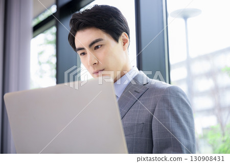 A man in a suit with a laptop, a consultant, or a salesman, thinking while looking at the screen A man in a suit with a laptop, a consultant, or a salesman, thinking while looking at the screen 130908431