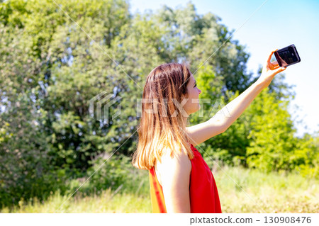 A young woman is taking a selfie while surrounded by a beautiful and scenic nature setting 130908476