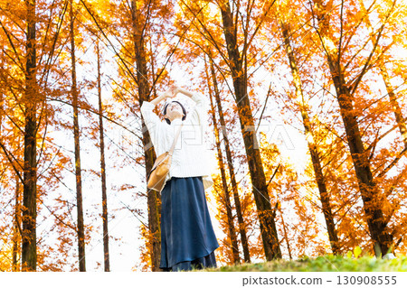Woman stretching her arms in a forest of autumn leaves Lifestyle image 130908555