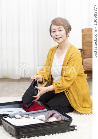 Senior woman packing for a trip Senior woman packing for a trip 130908777