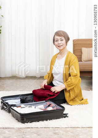 Senior woman packing for a trip 130908783