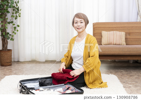 Senior woman packing for a trip Senior woman packing for a trip 130908786