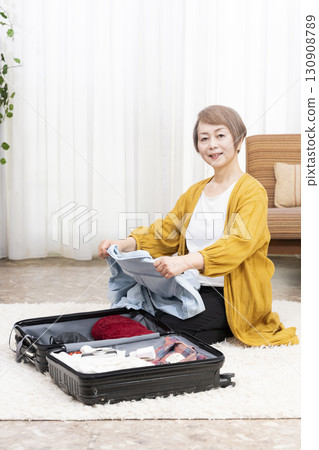 Senior woman packing for a trip Senior woman packing for a trip 130908789