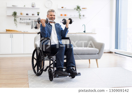 Mature Caucasian man in wheelchair exercising with dumbbells in bright indoor environment portraying determination, fitness, and healthy lifestyle. Well-dressed, middle-aged individual 130909142