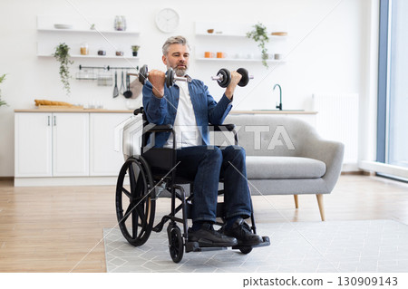 Mature Caucasian man seated in wheelchair, performing a workout with dumbbells indoors. Middle-aged adult engaged in strength training, promoting physical fitness and healthy lifestyle 130909143