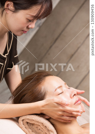 Young asian beautician doing facial massage. Young asian beautician doing facial massage. 130909456