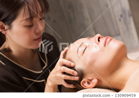 Young asian beautician doing head massage. 130909459