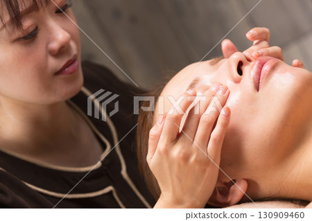 Young asian beautician doing facial massage. Young asian beautician doing facial massage. 130909460