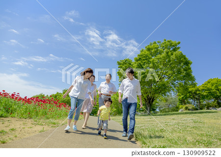 A three-generation family walking through a poppy-filled park A three-generation family walking through a poppy-filled park 130909522