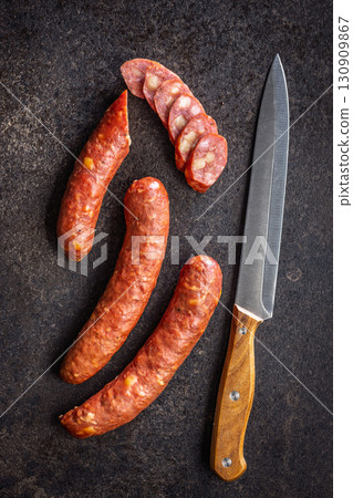 Smoked sausages and knife on black table. Top view. 130909867
