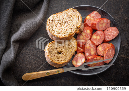 Smoked sliced sausages and bread on plate on black table. Top view. 130909869