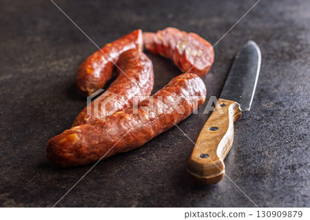 Smoked sausages and knife on black table. 130909879