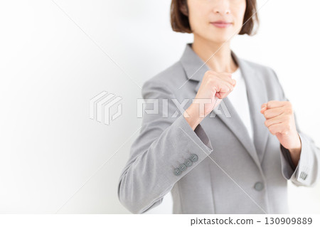 一位身穿灰色西裝的中年女商人擺出一副打鬥姿勢 130909889
