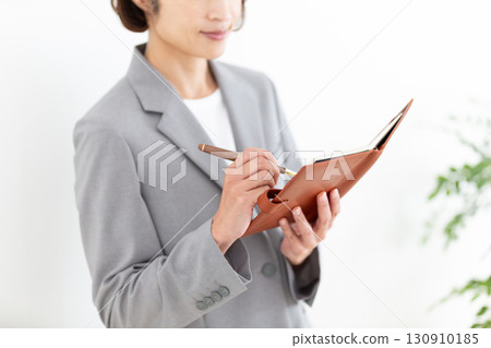 A middle-aged female businesswoman in a gray suit looking at her notebook A middle-aged female businesswoman in a gray suit looking at her notebook 130910185