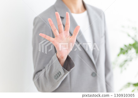 A middle-aged female businesswoman in a gray suit holding up five fingers 130910305