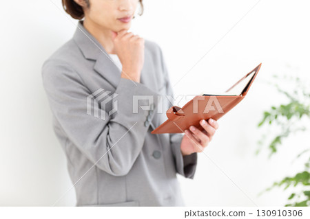 一位身穿灰色西裝的中年女商人正在看她的筆記本 130910306