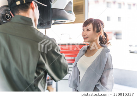 A female customer and a male mechanic receive an explanation about car maintenance and inspection at a repair shop A female customer and a male mechanic receive an explanation about car maintenance and inspection at a repair shop 130910337