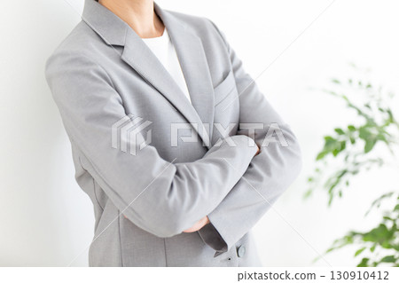 一位身穿灰色西裝、雙臂交叉的中年女商人 130910412