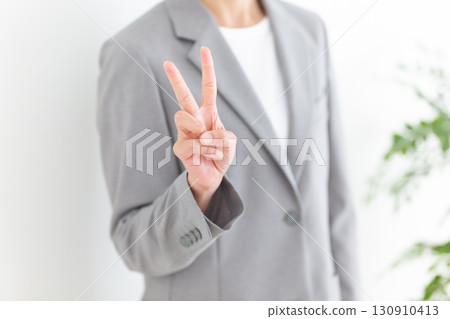 A middle-aged female business woman in a gray suit holding up two fingers A middle-aged female business woman in a gray suit holding up two fingers 130910413