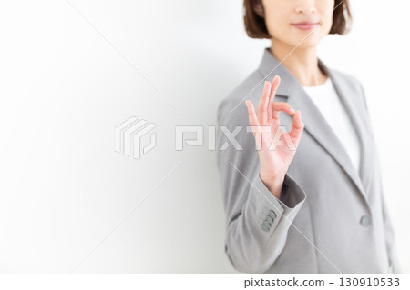 A middle-aged female business woman in a gray suit making a circle sign A middle-aged female business woman in a gray suit making a circle sign 130910533