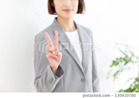 A middle-aged female business woman in a gray suit holding up two fingers A middle-aged female business woman in a gray suit holding up two fingers 130910780