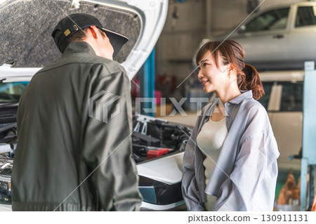 一名機械師在汽車引擎室向一名女顧客解說，一名男性機械師工作人員 130911131