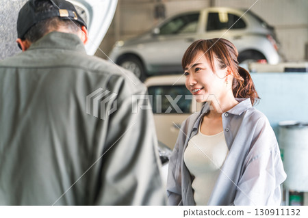 一名機械師在汽車引擎室向一名女顧客解說，一名男性機械師工作人員 130911132