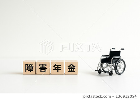 殘障退休金概念，帶有木塊“殘障退休金”和白色背景的微型輪椅 130912054