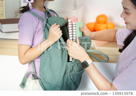 Back to School. A young girl excitedly packing her backpack with school supplies. 130913078