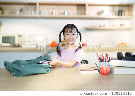 Back to School. Cheerful girl packing her backpack with school supplies. Back to School. Cheerful girl packing her backpack with school supplies. 130913112