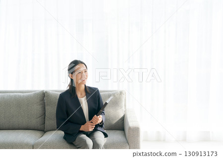 一位女士在客廳的沙發上操作智慧型手機 一位女士在客廳的沙發上操作智慧型手機 130913173