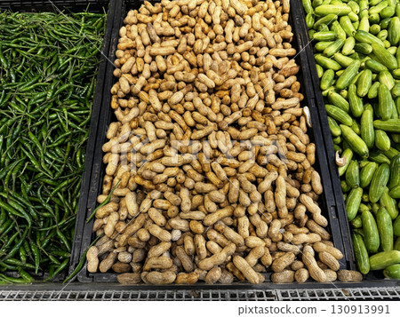 Trays of unshelled peanuts and green vegetables arranged in a market produce section Trays of unshelled peanuts and green vegetables arranged in a market produce section 130913991