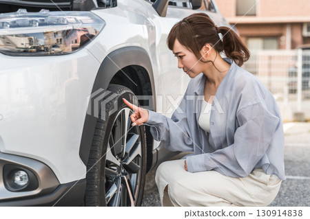 一名女司機檢查她的汽車輪胎(日常檢查) 一名女司機檢查她的汽車輪胎(日常檢查) 130914838